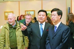 潘义奎（中）向中国驻圣彼得堡总领事季雁池介绍油画作品。