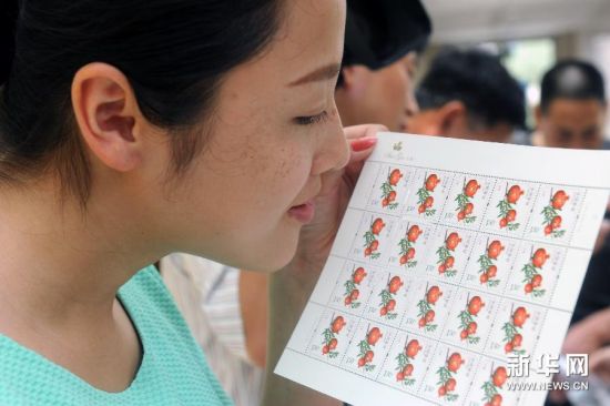 7月15日，山东省枣庄市峄城区一名集邮爱好者在闻《水果（一）》（石榴）特种邮票散发的香味。