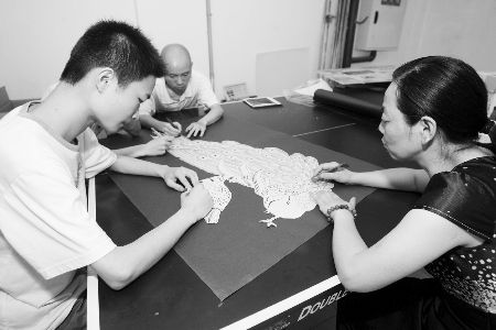 彭茂林（右）与员工创作剪纸工艺品。 记者 邹飞 摄