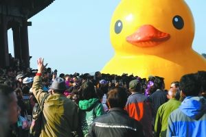 昨天，颐和园昆明湖边，游客们向“大黄鸭”挥手再见。 本报记者 和冠欣摄