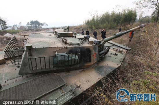 12月4日，浙江台州，人们在坦克前围观。这辆坦克买来还没几天，在郊区的一次试开中，不小心陷入了沟里，导致左前方履带损坏，无法动弹。