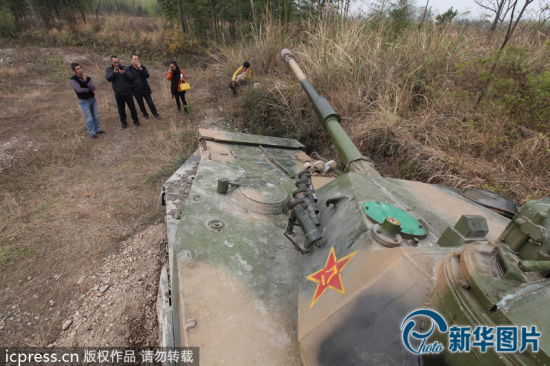 12月4日，浙江台州，人们在坦克前围观。这辆坦克买来还没几天，在郊区的一次试开中，不小心陷入了沟里，导致左前方履带损坏，无法动弹。