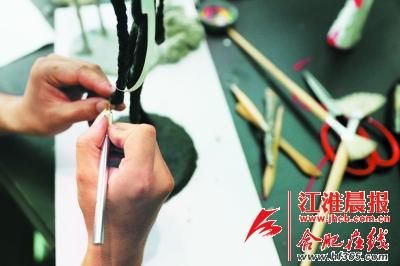 李绍正在用刻刀修饰作品。