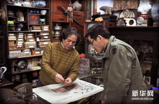 王锦思（右）在长春市和平大世界古玩城一间店铺内与店主讨论一件伪满时期的藏品（12月5日摄）。 新华社记者 许畅 摄