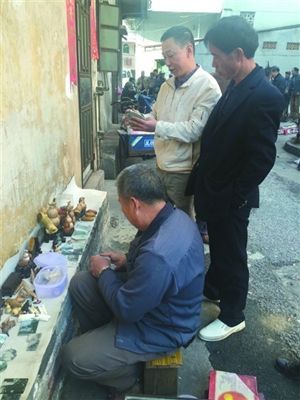 两名古玩爱好者在早市上查看玉石原料。 