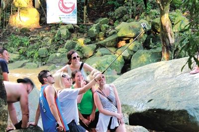 当地时间2014年12月3日，泰国苏梅岛，外国游客在景区用自拍杆合影。