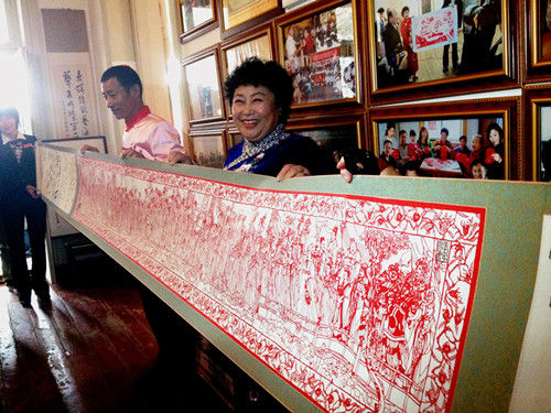 朱曼华正在展示其创作的长达9米的剪纸作品(王倩 摄)