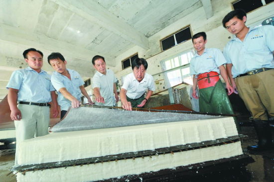 邢春榮（右三）向工人傳授撈紙技藝。