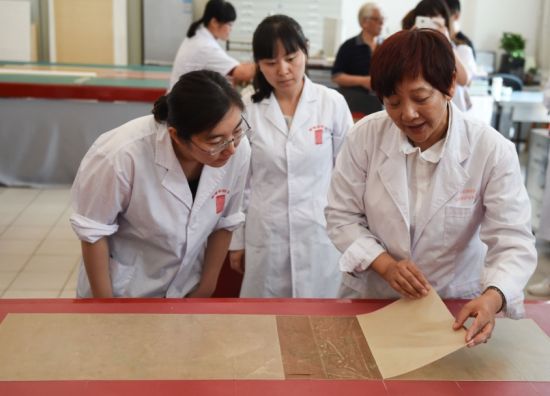 5月27日，首都博物馆书画装裱专家楼朋竹（右一）在展示利用生物揭展剂把一幅古书画的背纸轻松完整揭离。