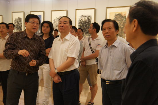 穆家善在中国美术馆画展上向中宣部副部长黄坤明和中国艺术研究院院长王文章讲解自己创作焦墨画的艺术理念