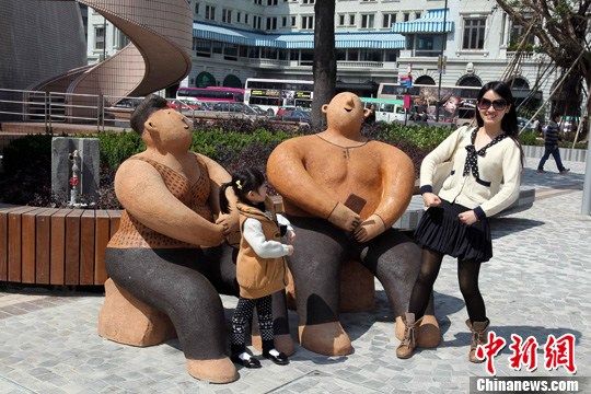 2月23日，访港游客在《心满意足》系列雕塑前快乐留影。中新社发 洪少葵 摄