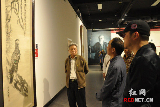 湖南本土知名画家杨福音[左]、朱训德[中]等，在展出作品前细细品味交流。