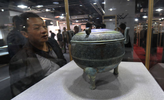 4月16日，一名收藏爱好者在湖南文物精品展上欣赏一件展出的春秋龙纹鼎。